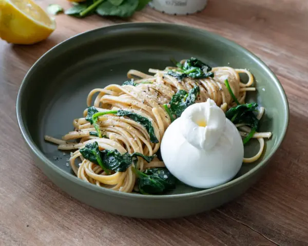 Pasta mit Spinat, Zitrone, Sahne und Parmesan, gekrönt von einem cremigen Burrata.