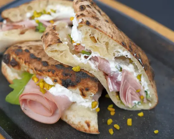 Pizza Mortadella e Pistacchio: knuspriges Brot gefüllt mit Mortadella, cremigem Käse und gehackten Pistazien. Ein Genuss!