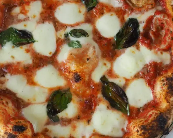 Perfekte Pizza Margherita, wie nach dem Caputo Pizzateig Rezept gemacht, mit geschmolzenem Mozzarella, Tomatensauce und frischem Basilikum.