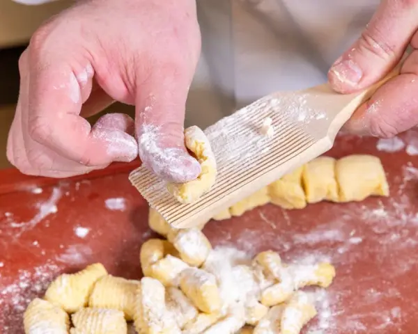 Hände formen Gnocchi mit einem Gnocchi-Brett. Köstliche italienische Gnocchi Rezepte beginnen so.
