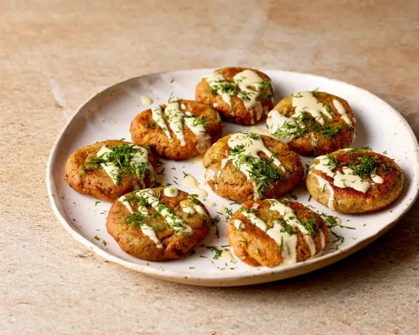 A plate of Sarde in Saor, small, round fish cakes drizzled with creamy sauce and fresh dill.