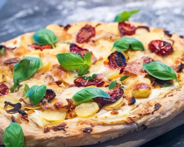 Leckeres Pizza Bianca Rezept mit Kartoffelscheiben, getrockneten Tomaten und frischem Basilikum.