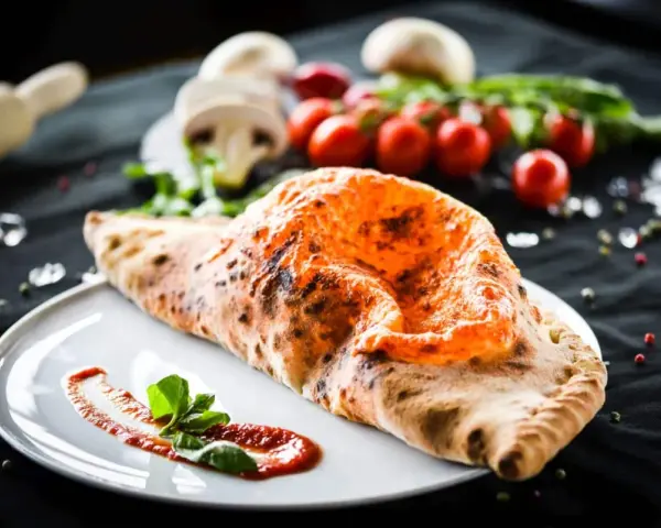 Ein köstlicher, original italienischer Calzone, goldbraun gebacken, mit Tomatensoße und Basilikum garniert.