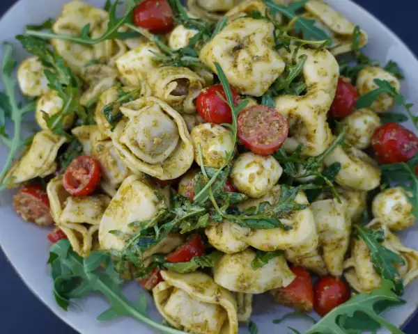 Tortellini Salat mit Rucola, Kirschtomaten und Mozzarella-Kugeln, alles in Pesto geschwenkt. Ein leichter Genuss!