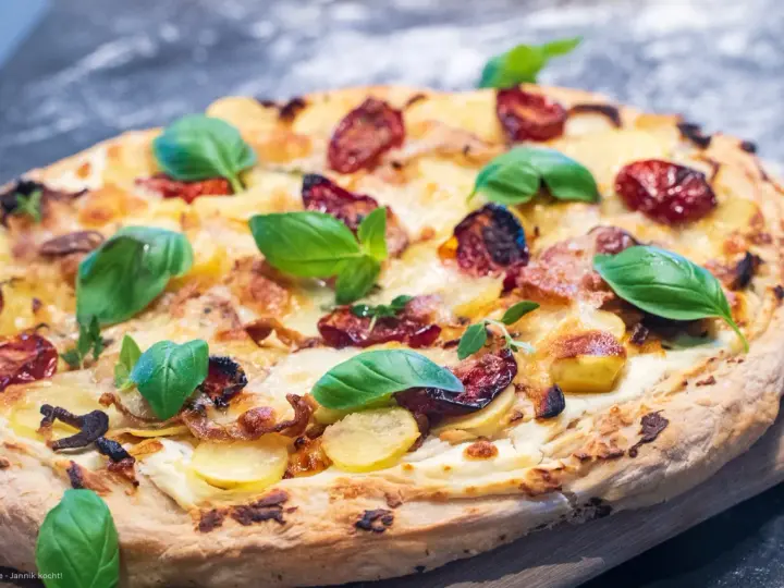 Leckeres Pizza Bianca Rezept mit Kartoffelscheiben, getrockneten Tomaten und frischem Basilikum.
