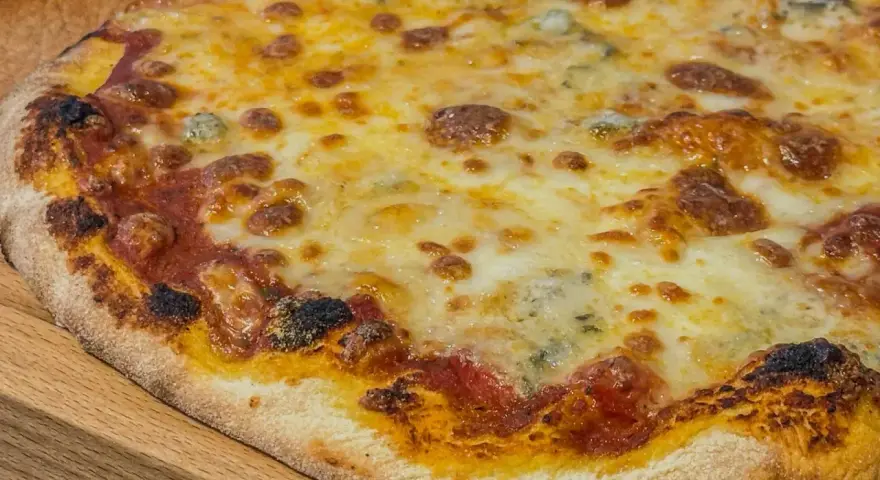 Eine köstliche quattro formaggi Pizza mit geschmolzenem Käse und knusprigem Rand auf einem Holzbrett.