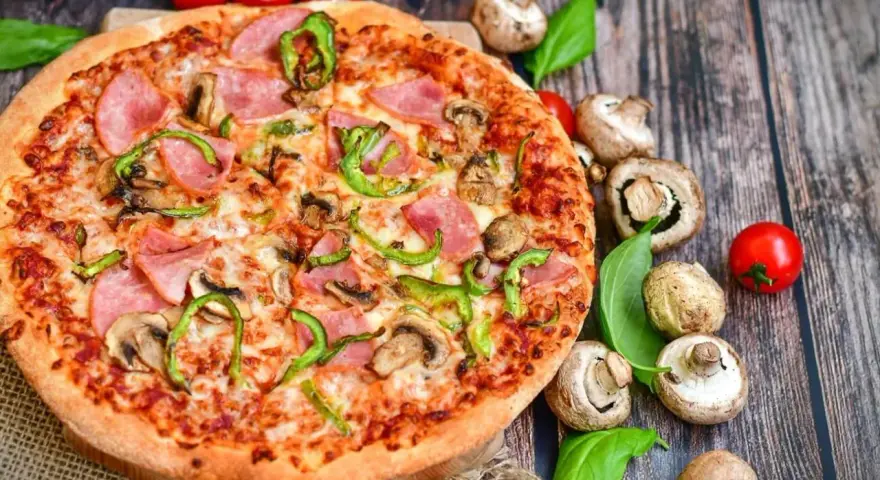 Eine leckere Pizza mit Schinken, Pilzen und Paprika. Die Frage "wie viel Kalorien hat eine Pizza" bleibt bei diesem Anblick offen.