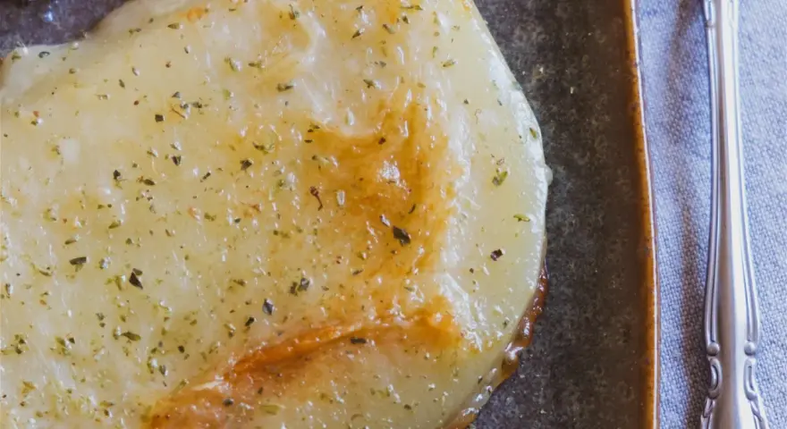 Gebratener Käse mit Kräutern, eine köstliche caciocavallo alternative, auf dunkler Platte mit Gabel.