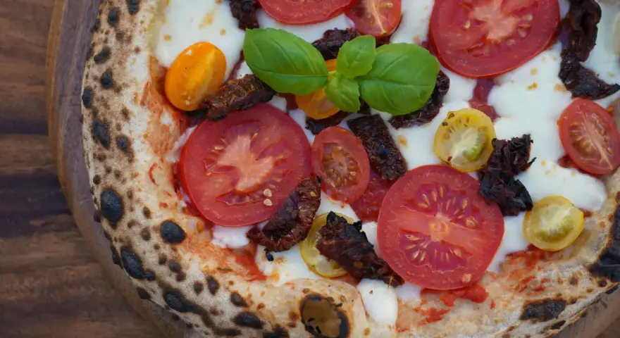 Pizza mit frischen Tomaten, Mozzarella, Basilikum und intensiven pomodorini secchi.