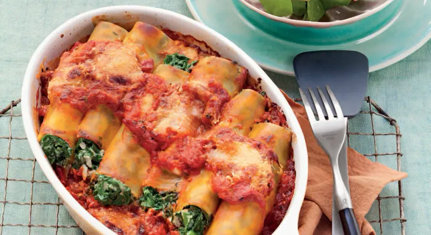 Cannelloni ricotta-spinat italienisch, überbacken mit Tomatensauce und Käse, serviert in einer Auflaufform.