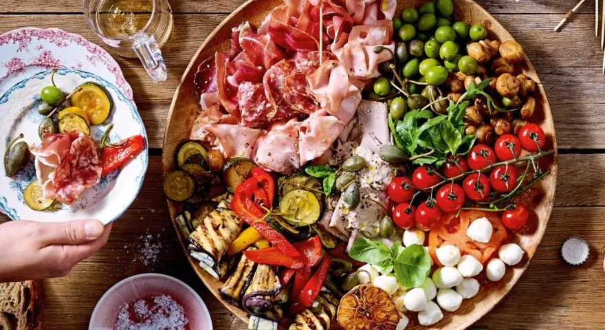 Italienische Snacks Rezepte: Eine üppige Platte mit Aufschnitt, gegrilltem Gemüse, Oliven, Tomaten und Mozzarella. Perfekt für einen Aperitif!
