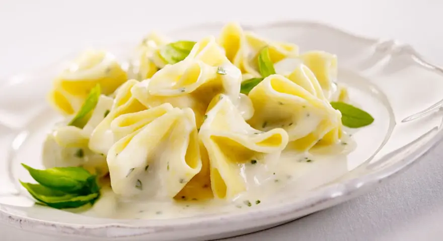 Gefüllte Pasta in cremiger Basilikum-Sahne-Sauce, garniert mit frischen Basilikumblättern. Ein Genuss für Gaumen und Auge.