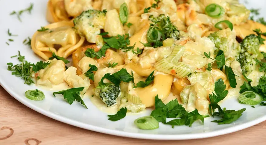 Tortellini mit Brokkoli und Blumenkohl in cremiger Sauce, garniert mit Petersilie. Lecker, wenn man Tortellini anbraten möchte.