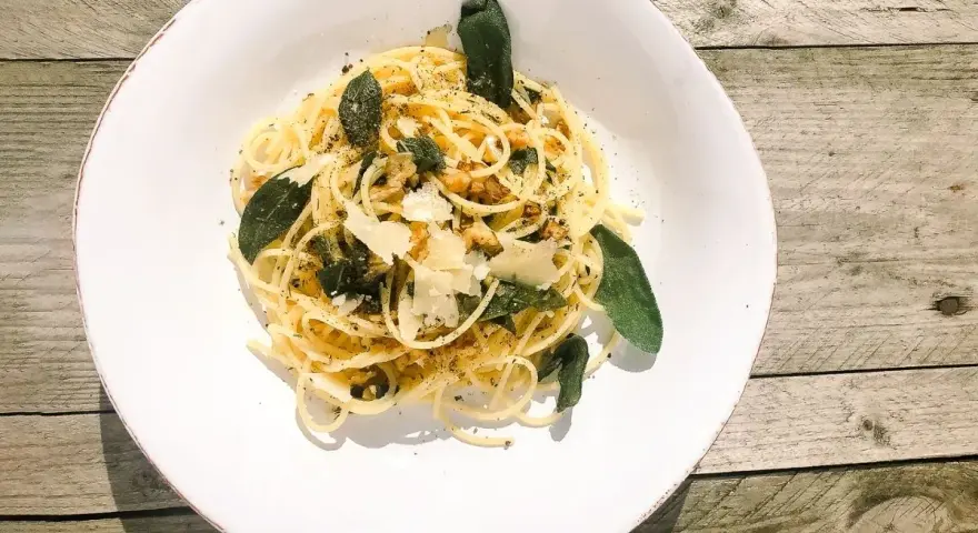 Spaghetti in Salbeibutter mit Parmesan und Walnüssen, garniert mit frischen Salbeiblättern.