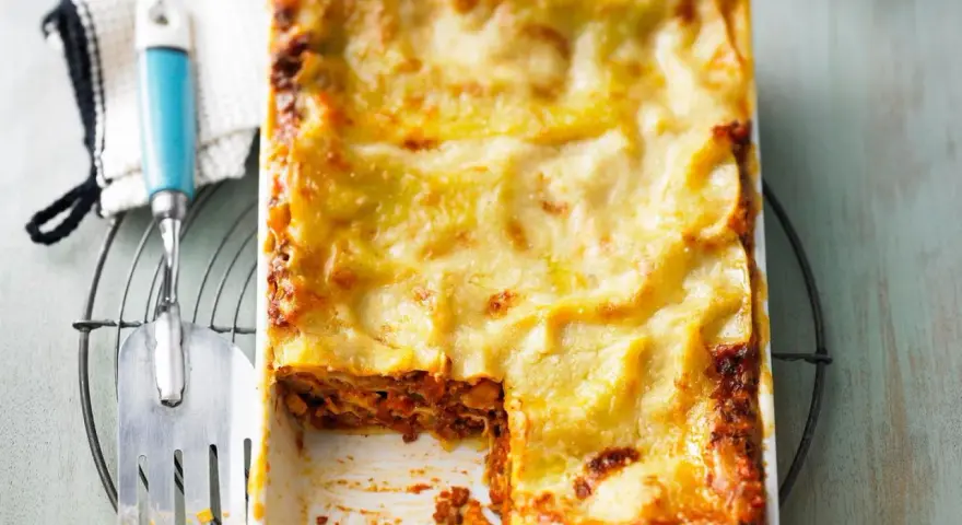 Ein frisch gebackenes, goldbraunes Lasagne-Rezept, original italienisch, mit einer Portion entnommen.