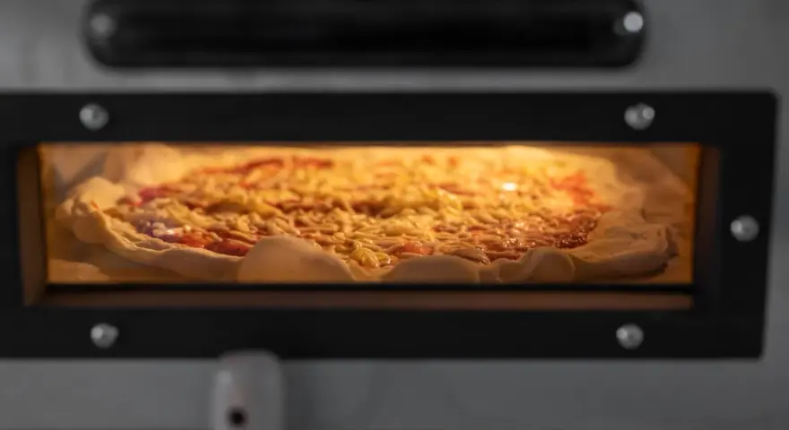 Eine Pizza mit Käse und Tomatensauce backt in einem Ofen.