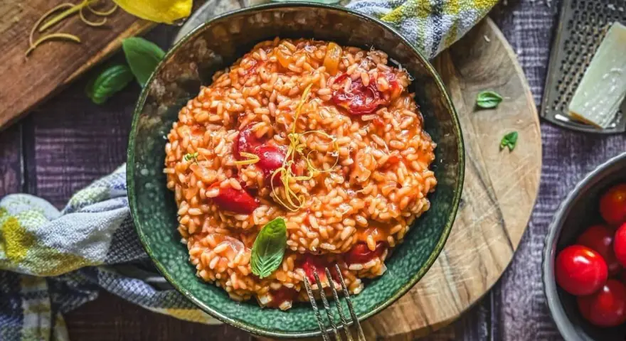 Cremiges Tomaten-Risotto, ein einfaches und köstliches Risotto Rezept, garniert mit Basilikum und Zitronenzeste.