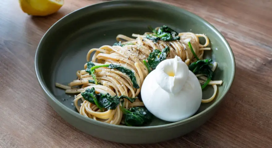 Pasta mit Spinat, Zitrone, Sahne und Parmesan, gekrönt von einem cremigen Burrata.