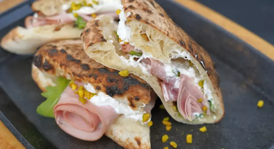 Pizza Mortadella e Pistacchio: knuspriges Brot gefüllt mit Mortadella, cremigem Käse und gehackten Pistazien. Ein Genuss!