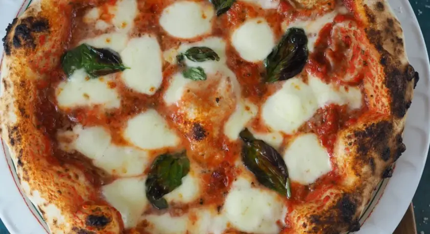 Perfekte Pizza Margherita, wie nach dem Caputo Pizzateig Rezept gemacht, mit geschmolzenem Mozzarella, Tomatensauce und frischem Basilikum.