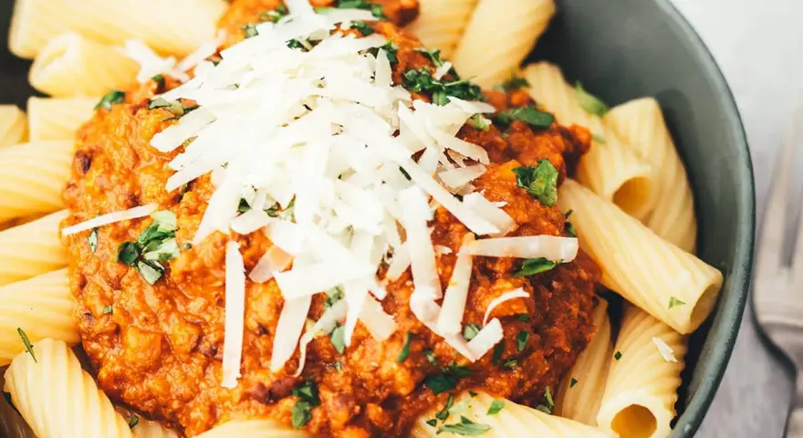 Ein Teller Rigatoni mit Bolognese und Parmesan. Sind Nudeln leicht verdaulich? Diese hier sehen köstlich aus!