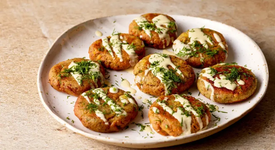 A plate of Sarde in Saor, small, round fish cakes drizzled with creamy sauce and fresh dill.