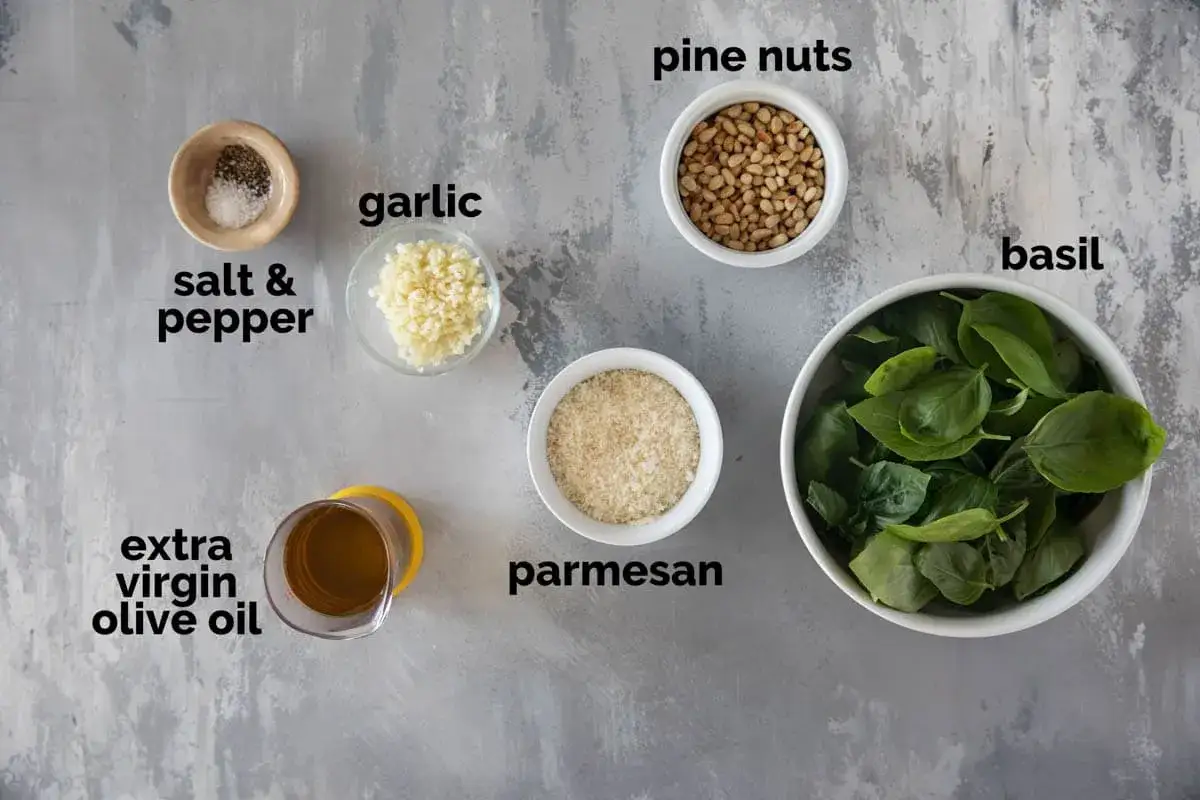 Zutaten für italienisches Pesto: frischer Basilikum, Pinienkerne, Knoblauch, Parmesan, Olivenöl, Salz und Pfeffer.
