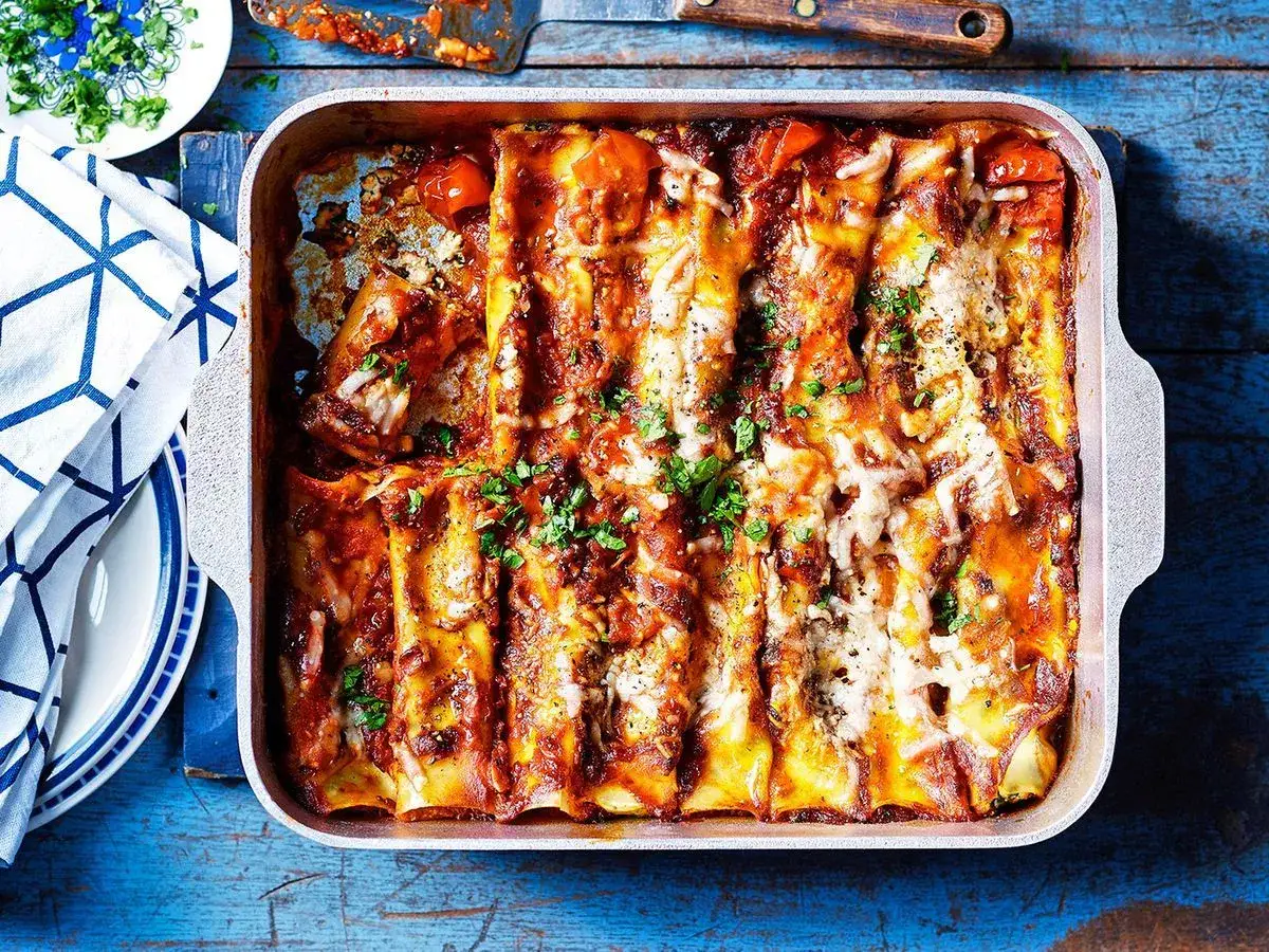 Herzhafte Cannelloni Ricotta-Spinat, italienisch überbacken mit Tomatensauce und Käse, garniert mit Petersilie.