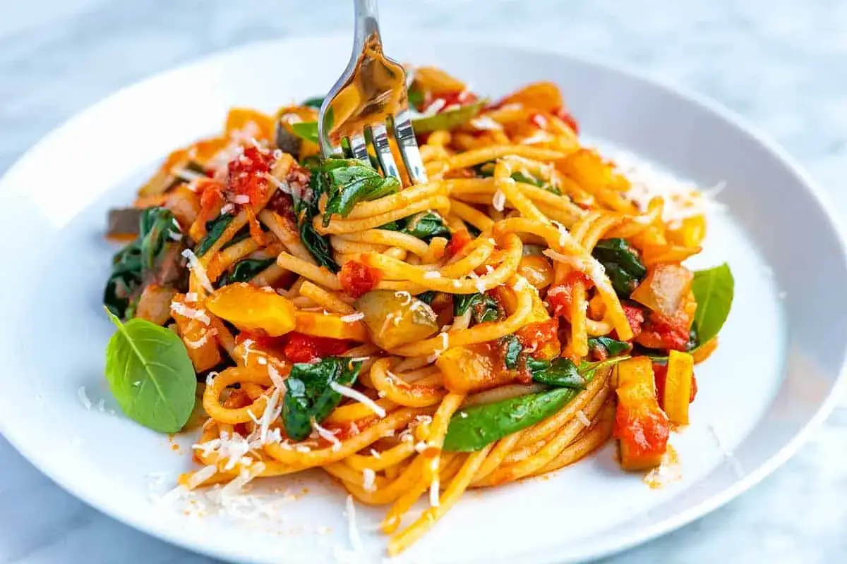 Ein Teller Spaghetti mit Gemüse, Tomaten und Parmesan. Ein perfektes Beispiel für ausgefallene Pasta Rezepte, das Lust auf mehr macht.