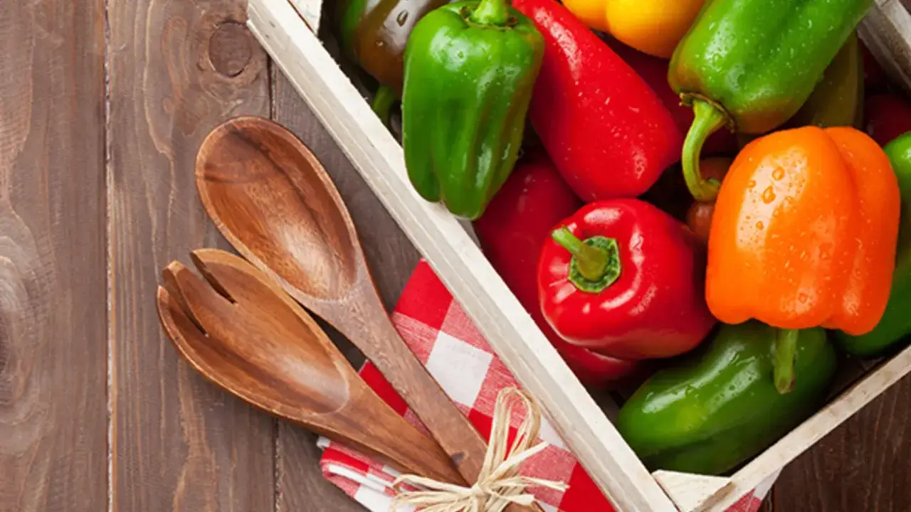 Bunte Peperoni in einer Holzkiste, bereit für die Zubereitung. Was ist Peperoni? Bunte Paprika, die für Salate und Gerichte verwendet werden.