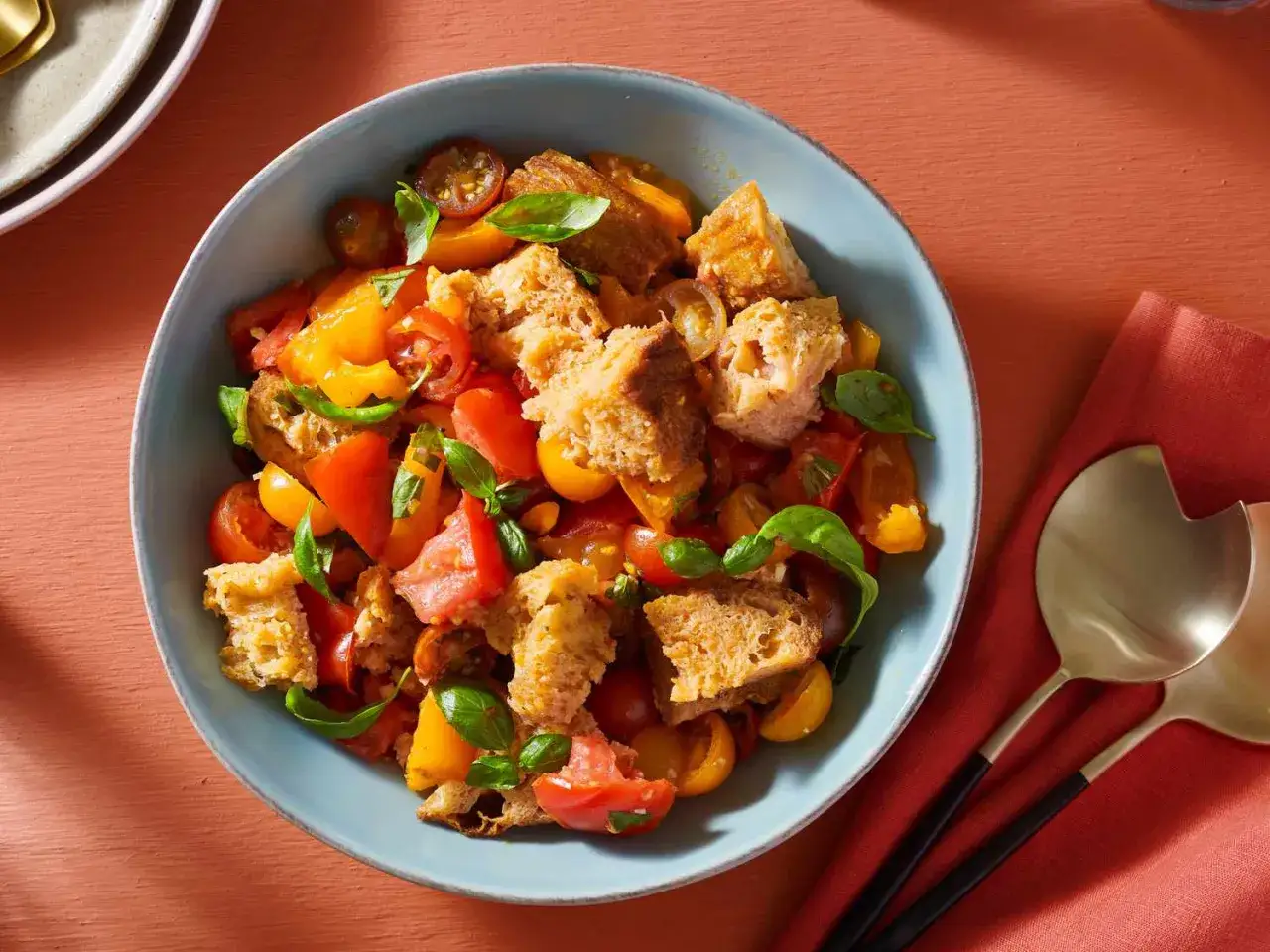 Ein köstliches Panzanella Rezept mit frischen Tomaten, Brotstücken und Basilikum in einer blauen Schüssel.