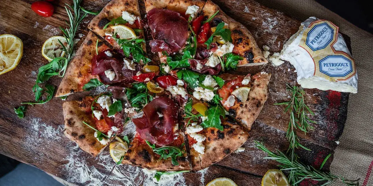 Pizza mit Bresaola, Rucola, Tomaten und Zitrone. Bresaola ist ein luftgetrocknetes Rindfleisch, das dieser Pizza eine herzhafte Note verleiht.