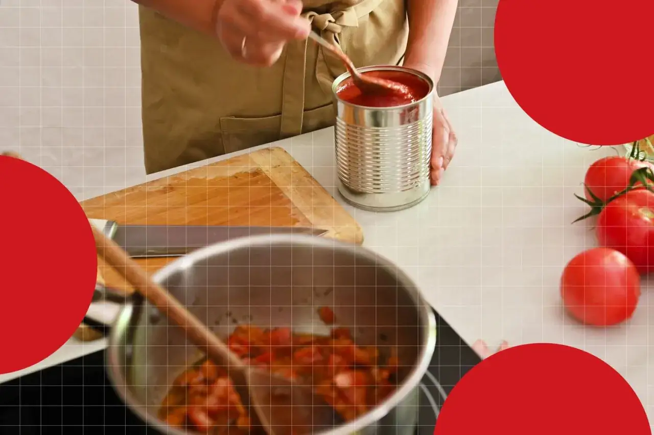 Person bereitet ein Gericht mit gehackten Tomaten aus der Dose zu. Ein Kochtopf mit Tomaten ist auf dem Herd, daneben eine Dose mit Tomaten.