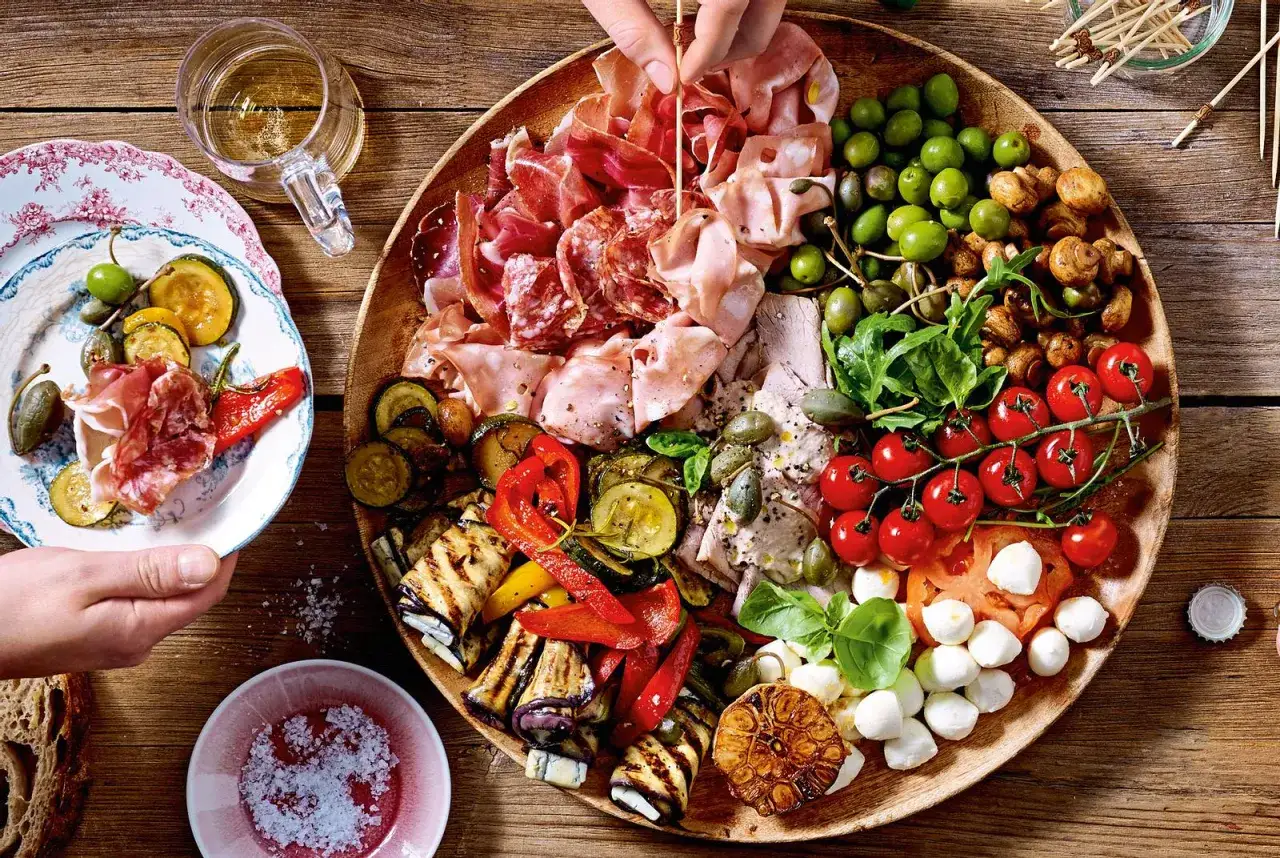 Eine üppige Platte mit italienischen Snacks: Wurst, Käse, Oliven, gegrilltes Gemüse und Tomaten. Perfekt für italienische Snacks Rezepte.
