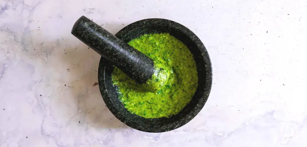 Frisches Basilikum wird im Mörser zermahlen, um ein authentisches pesto-rezept original zu kreieren.