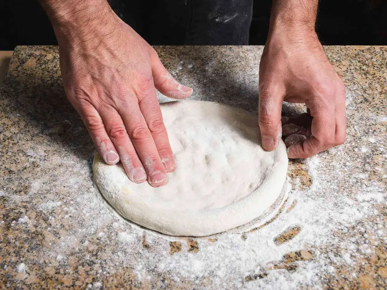 H&auml;nde formen den waldi pizzateig auf einer bemehlten Arbeitsfl&auml;che.