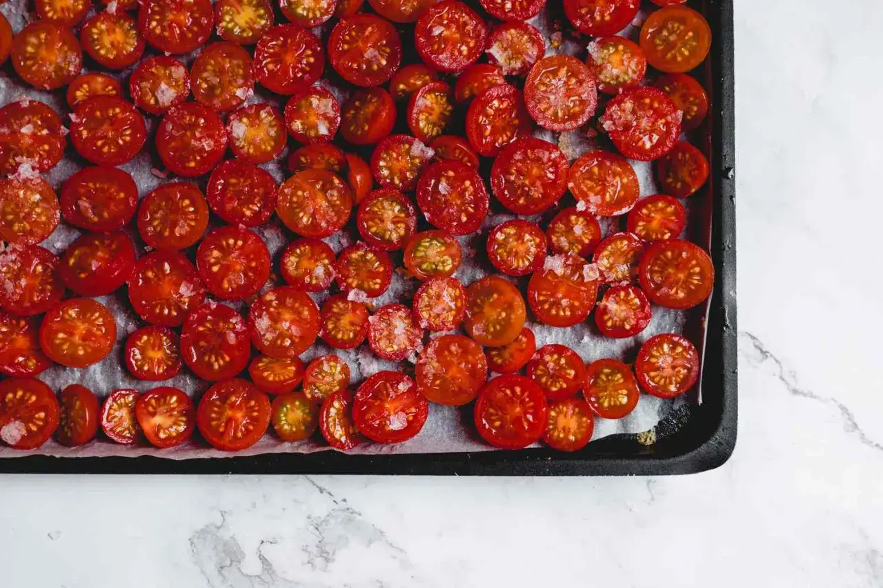 Halbierte Kirschtomaten, bereit zum Trocknen, mit grobem Salz bestreut. Diese pomodorini secchi werden bald ein intensives Aroma entfalten.