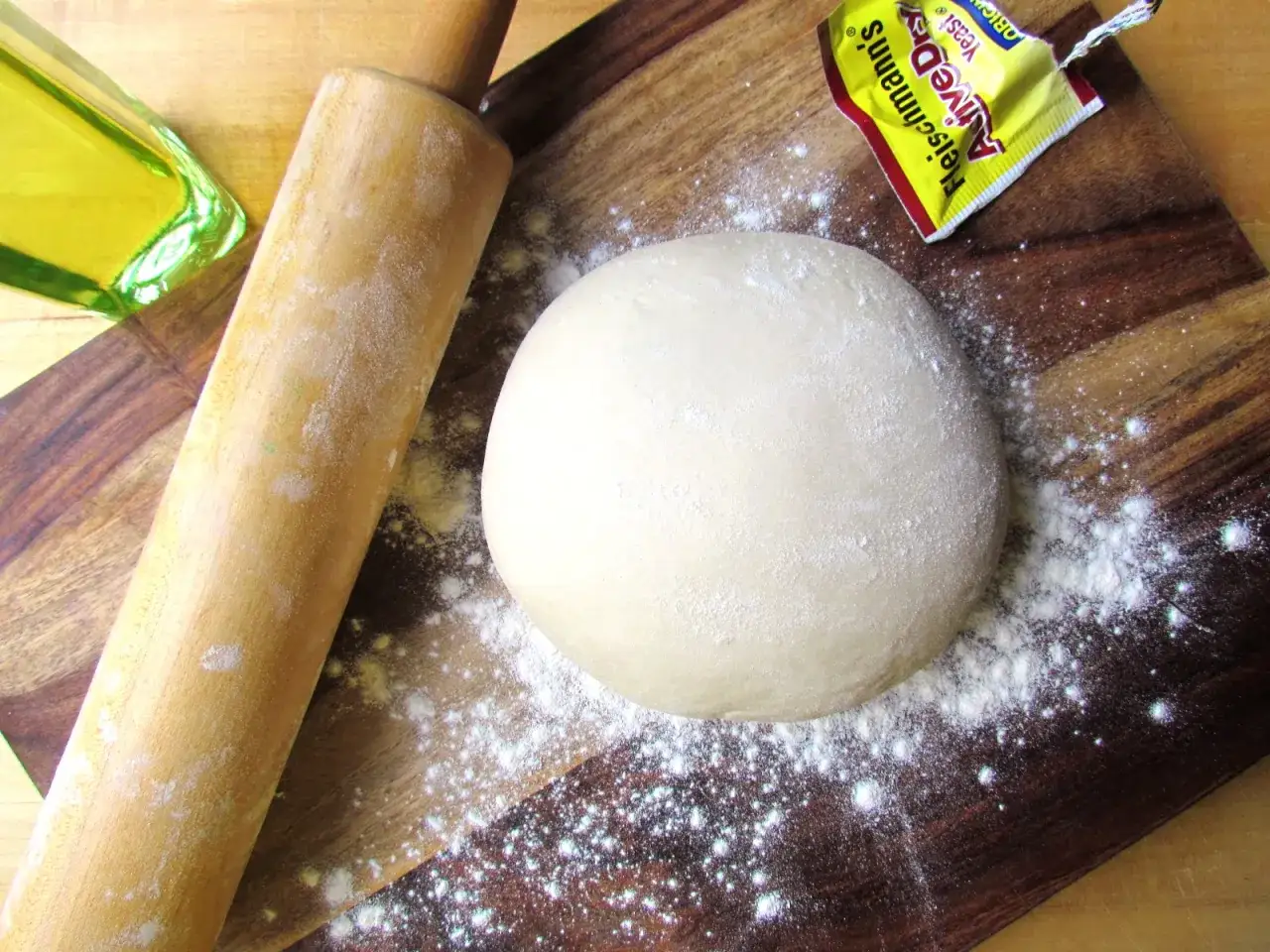Original italienischer pizzateig wenig hefe, bereit für die Zubereitung. Teigkugel, Nudelholz, Öl und Hefe auf Holzbrett.