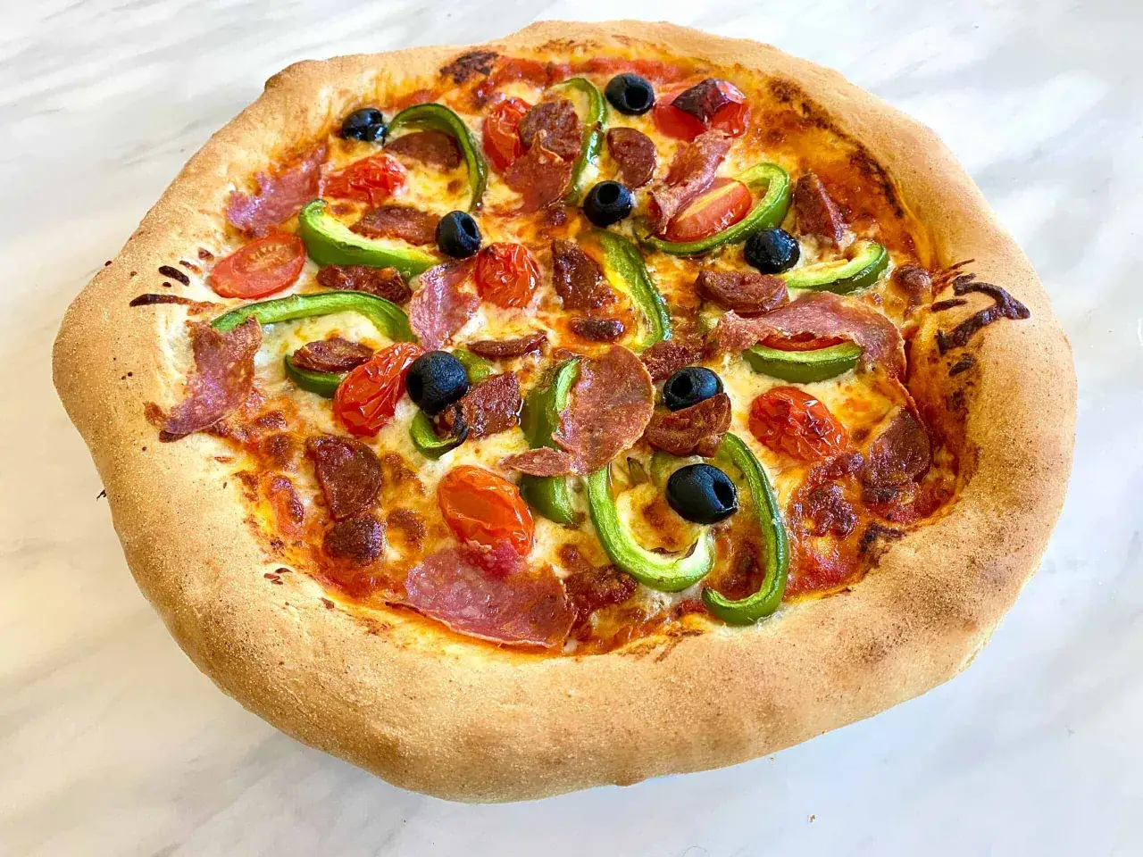 Eine köstliche Pizza mit Salami, Paprika, Tomaten und Oliven auf weltbestem Pizzateig mit Trockenhefe.