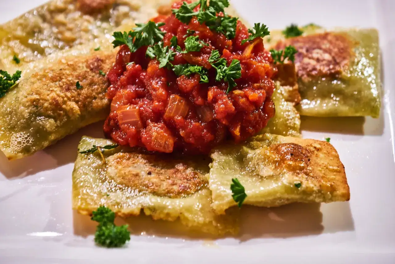 Goldbraun gebratene Ravioli mit frischer Tomatensauce und Petersilie &ndash; ein Genuss, der Lust auf die besten Ravioli Rezepte macht.