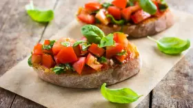 Zwei Bruschetta mit frischen Tomaten und Basilikum, garniert mit einem Hauch von Paprika, auf rustikalem Holz.