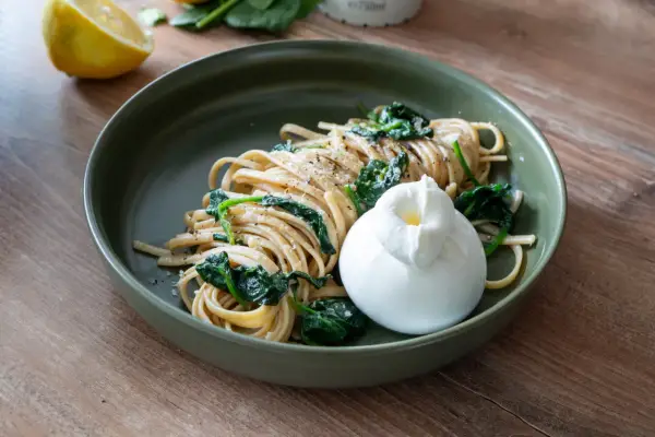 Pasta mit Spinat, Zitrone, Sahne und Parmesan, gekrönt von einem cremigen Burrata.