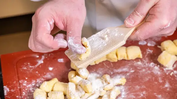 Hände formen Gnocchi mit einem Gnocchi-Brett. Köstliche italienische Gnocchi Rezepte beginnen so.